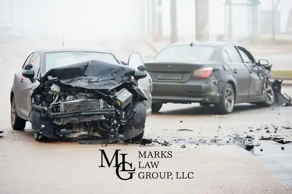 A car with a destroyed front end stopped in the road after a crash in fog