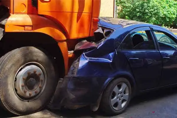 An orange semi-truck crushed into the rear of a blue sedan