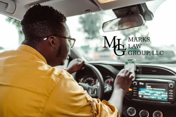 Driver looking at a phone in one hand while steering with the other