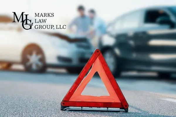 Red warning triangle on the road with two drivers inspecting a collision behind it