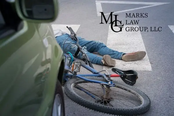 Cyclist lying on a crosswalk beside a fallen bicycle in front of a car
