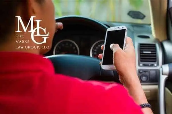 Driver in a red shirt holding a smartphone above the steering wheel