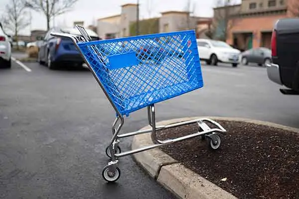 An abandoned blue shopping cart left in a store parking lot