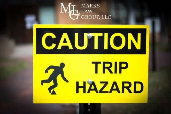 Yellow caution sign reading "Caution: Trip Hazard" with a stumbling figure icon
