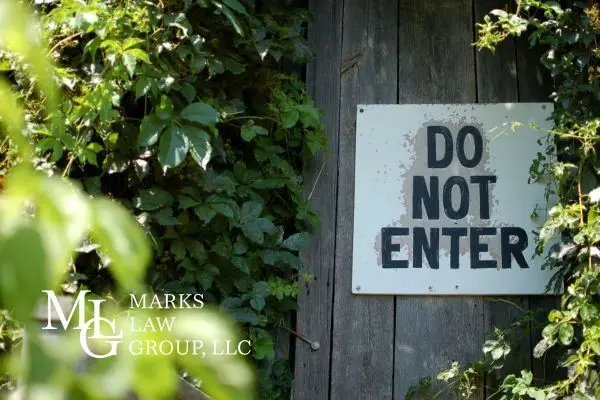 A weathered Do Not Enter sign on an ivy-covered wooden fence