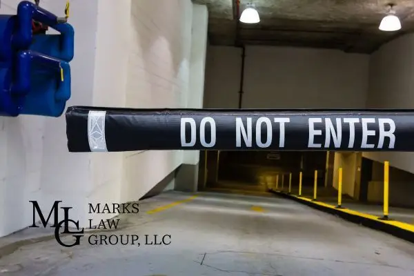 A black barrier arm reading Do Not Enter lowered across a parking garage ramp
